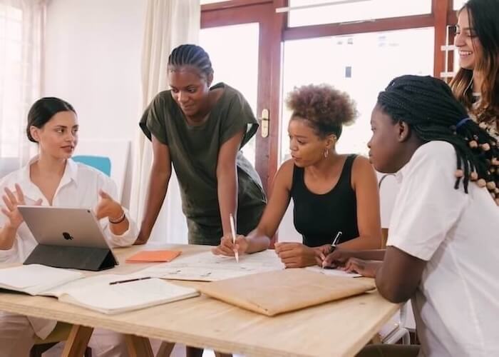 Women discussing a project around a table | Image for the Story Bridge Hotel testimonial.