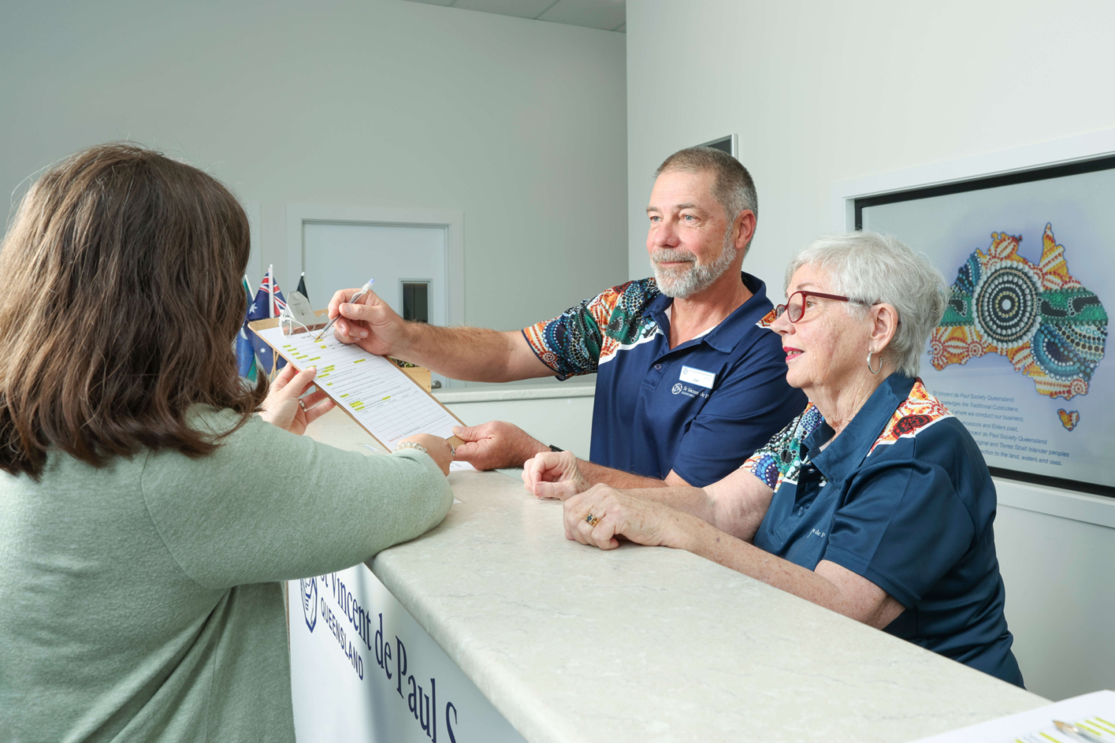 St Vincent de Paul volunteers assisting someone behind a desk.