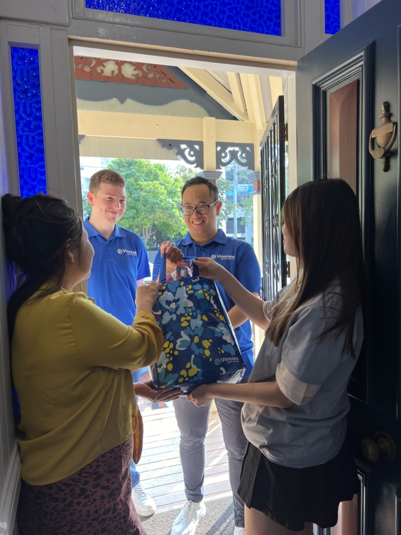 St Vincent de Paul volunteers delivering bag to two women inside a house