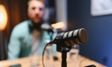 Man Recording Podcast with Microphone in Home Studio | Featured Image for the The Importance of Professional IVR Voice Recordings for Your Business blog.