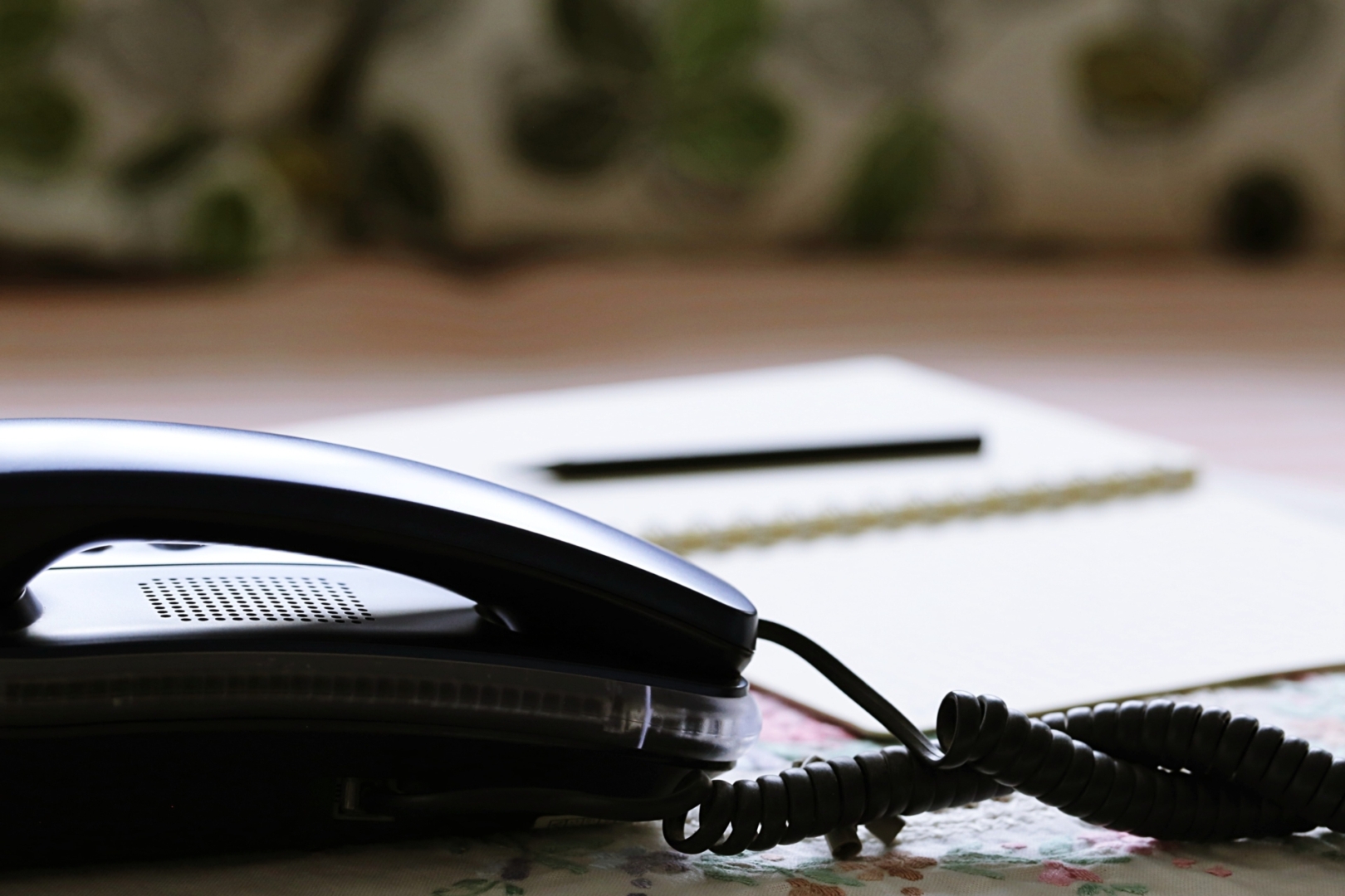 Telephone with notepad and pen on a table | Featured Image for the What to Include in Your On-Hold Phone Message Scripts for Maximum Impact blog.
